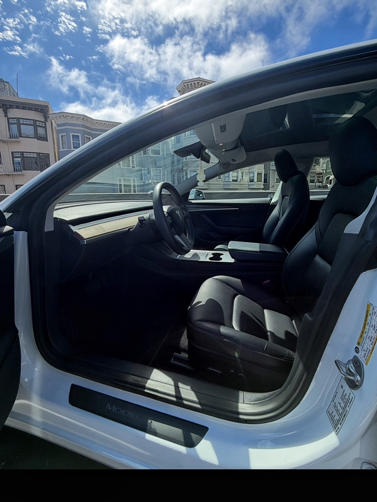 Streak-free glass and trim on a white Tesla Model 3 with San Francisco homes behind